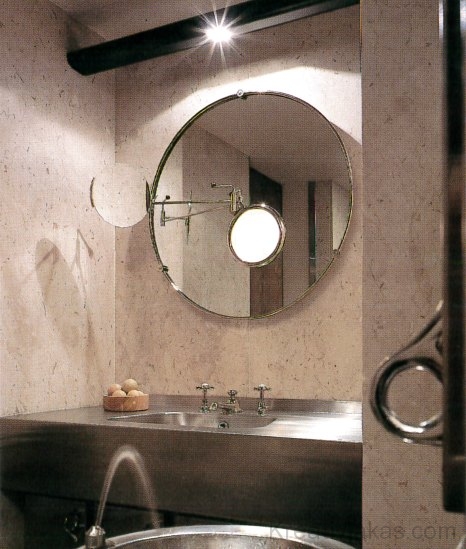  A fürdő­szobájában egy kis­feszültségű volfrám-halogénizzó keskeny nyalábja lép elő a kör alakú tükör fölött
